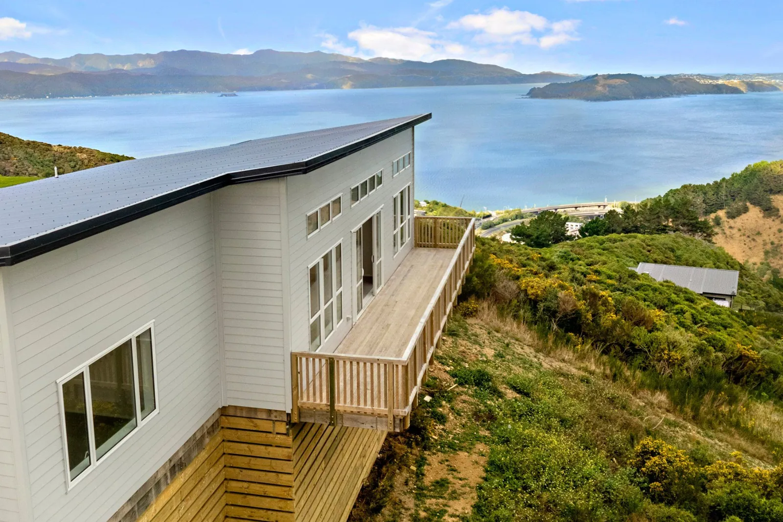 The completed Tānema home and its timber terrace above Wellington Harbour